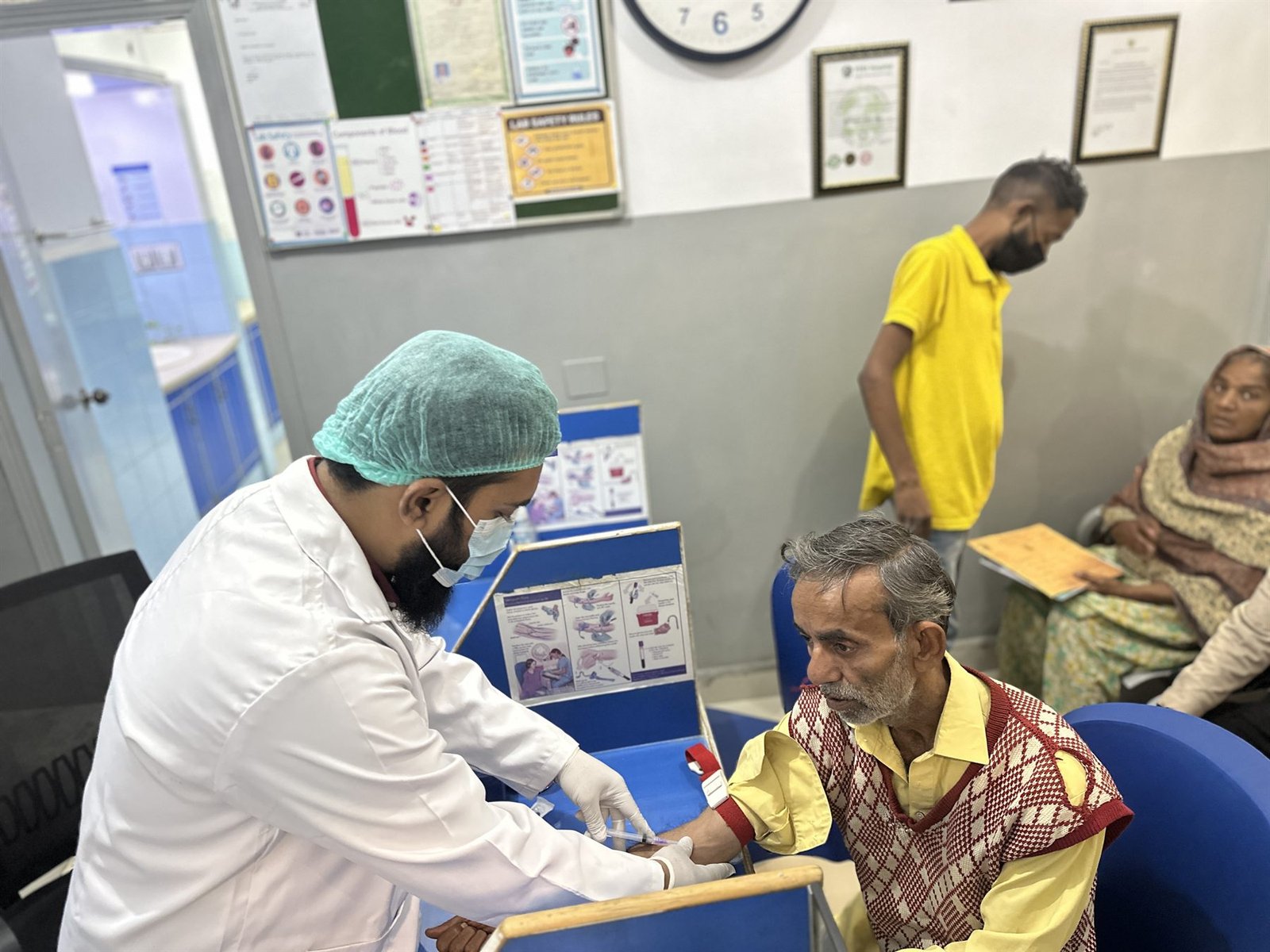 Phlebotomist collecting a blood sample from a patient at PEBS Hospital